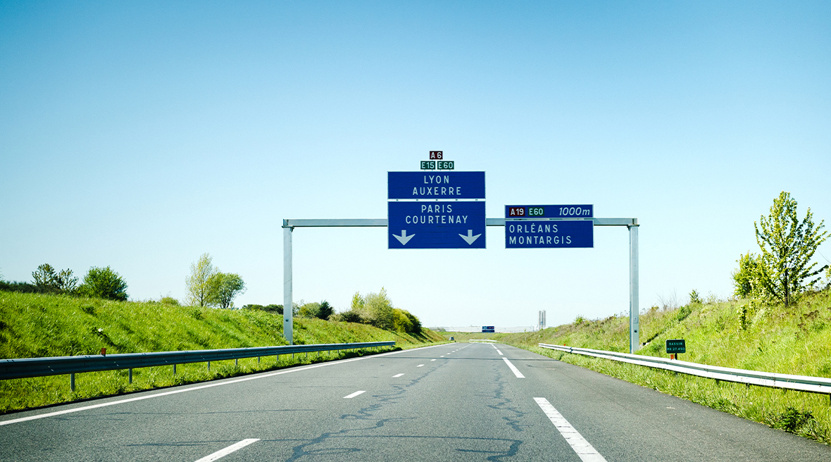 Empty French autoroute with overhead blue signs for Lyon, Auxerre, Paris and Orleans